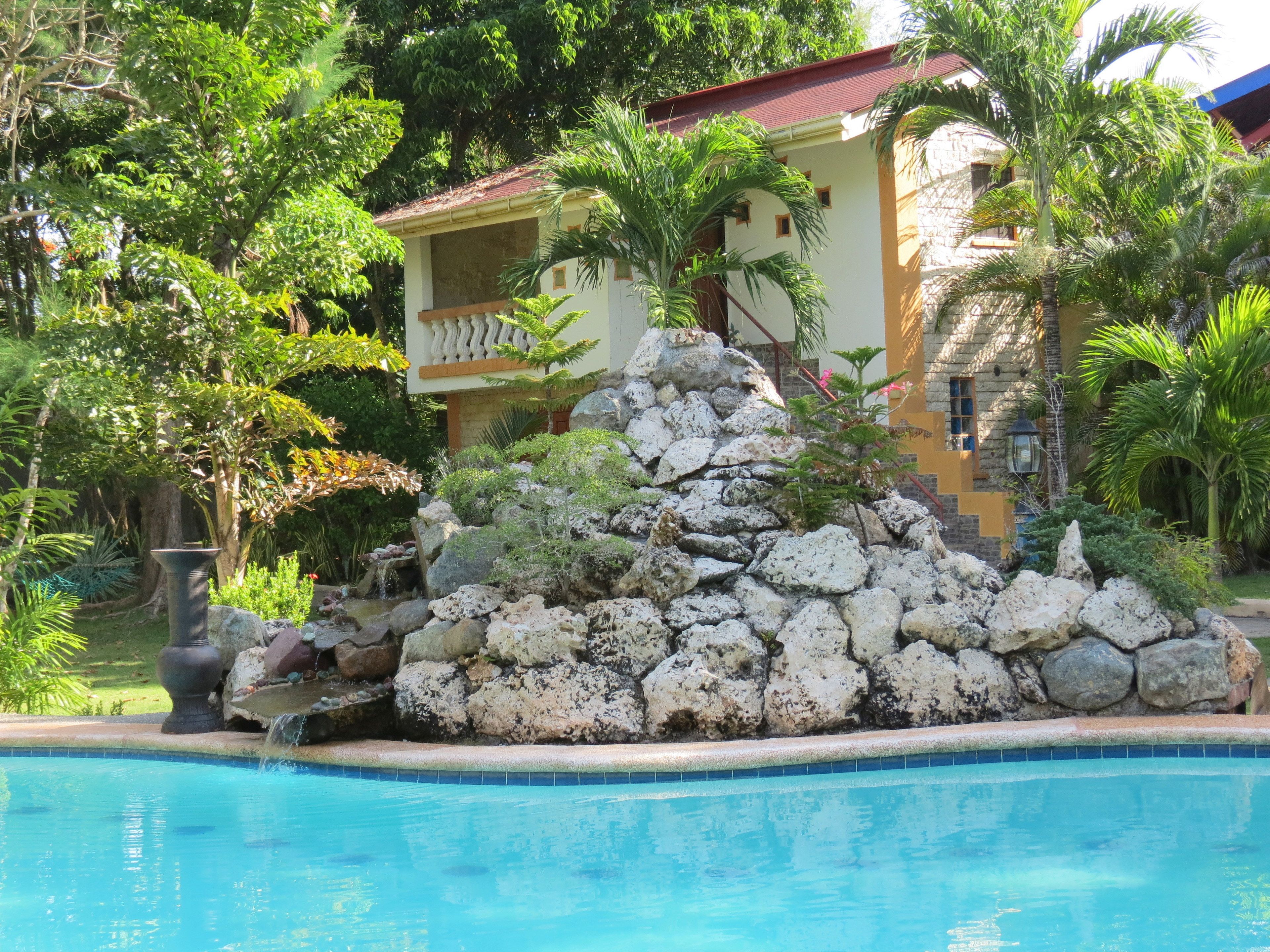 Ein Pool mit Felsen und einem Gebäude im Hintergrund.