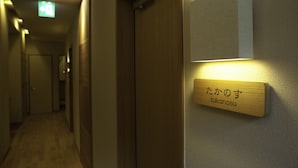 A hallway with a wooden door and a sign with Japanese characters. - Ryosaino Oyado Mizuhaso (Hatsukaichi)