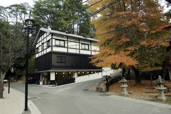 Un edificio japonés tradicional con fachada blanco y negro, tejado inclinado y una pequeña entrada con barandilla negra.