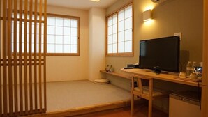A compact room with a tatami mat floor, a television, a small desk, and a refrigerator. - Ryosaino Oyado Mizuhaso (Hatsukaichi)