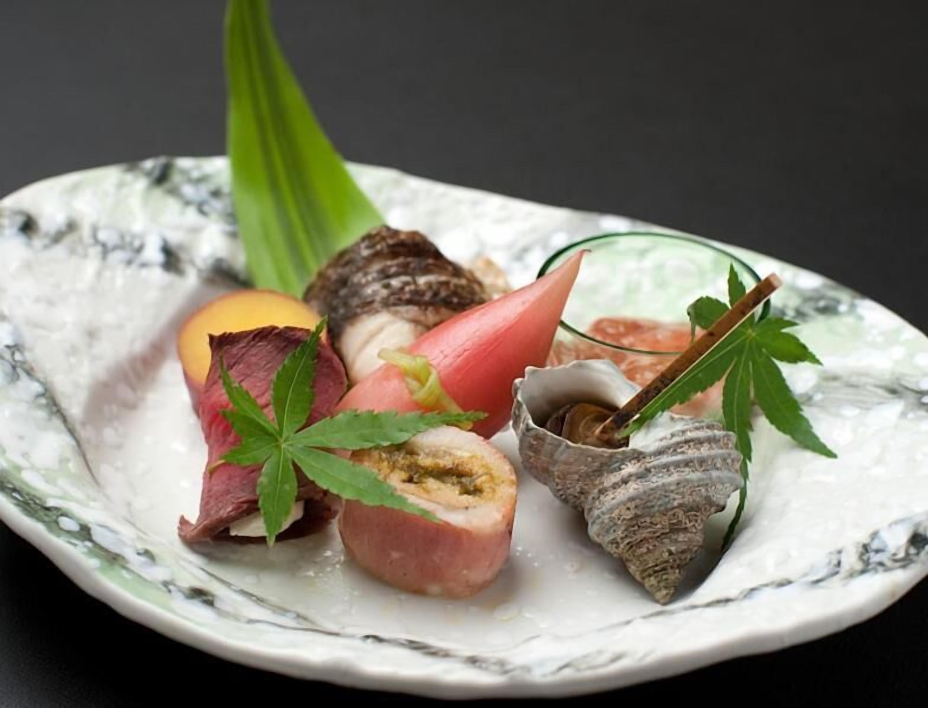 A plate with various food items including a piece of meat, a tomato, a mushroom, and a green leaf garnish.