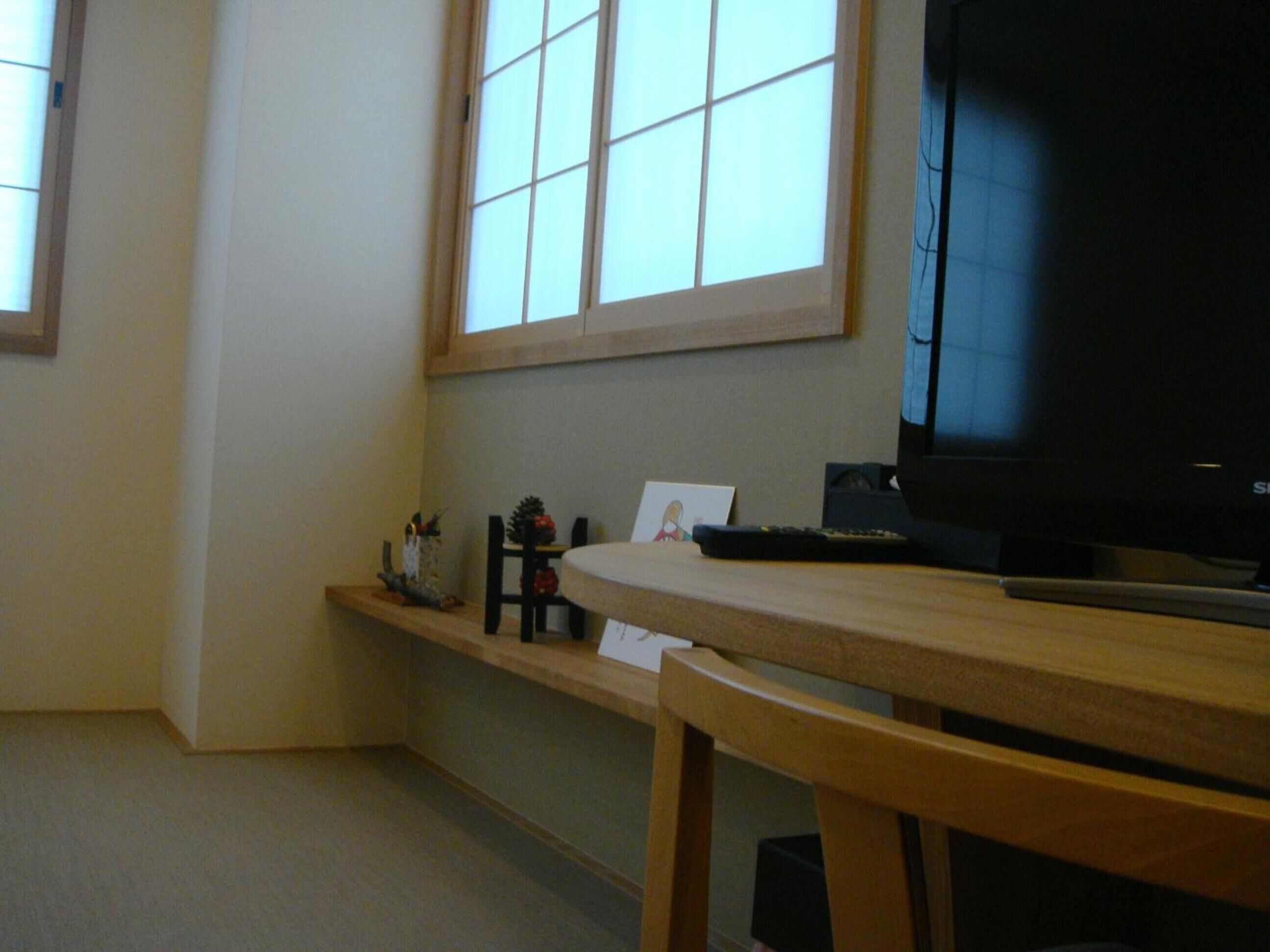 A room with a wooden table, a television, and a window with blinds.