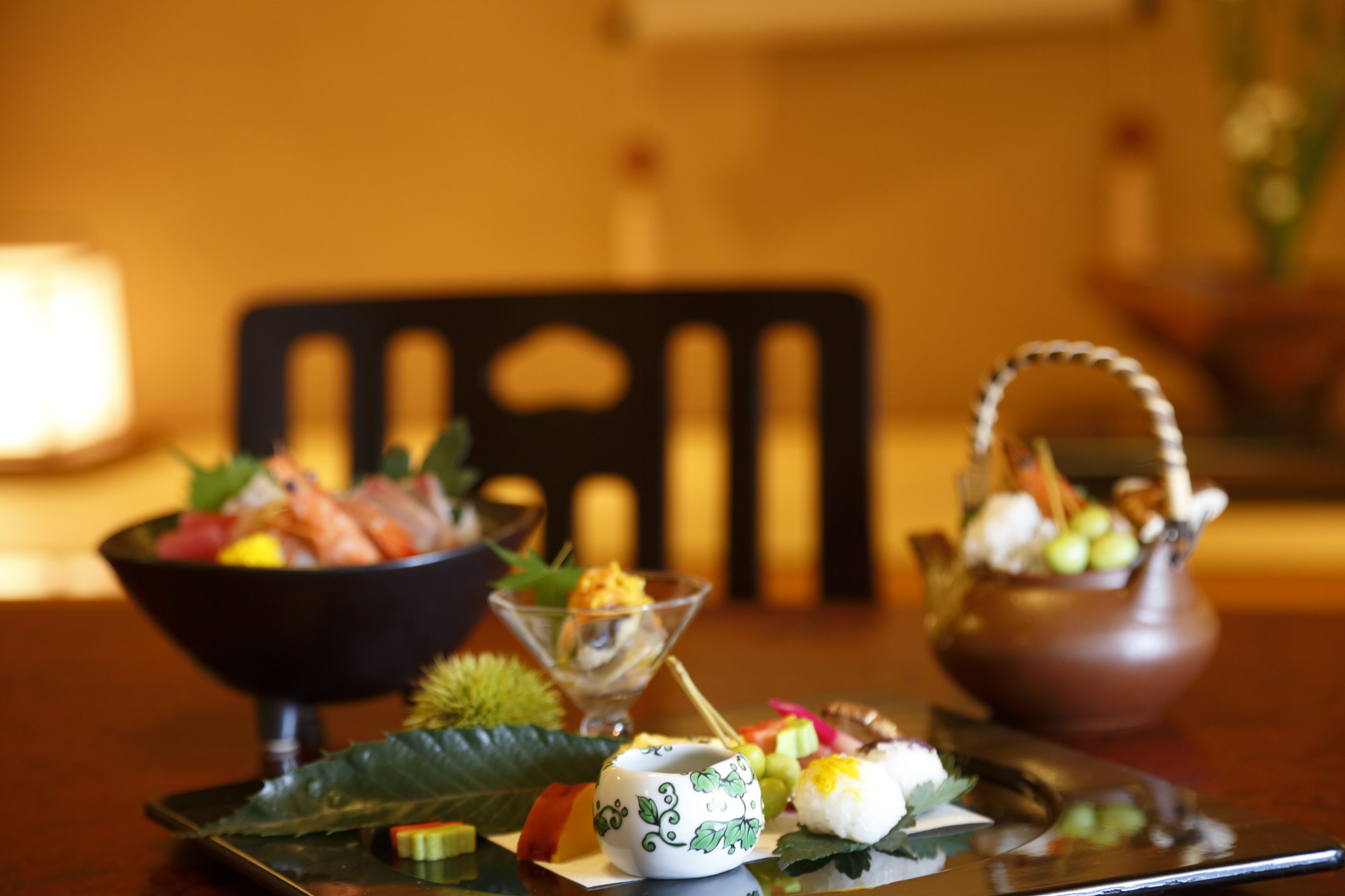 A table with various dishes, including sushi and a teapot.
