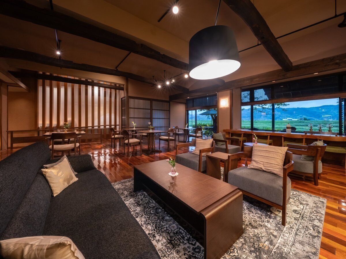 A spacious living area with a sofa, chairs, a coffee table, and a large window offering a view.