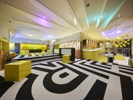 Un moderno vestíbulo de hotel con una recepción central, una escalera y una alfombra estampada.