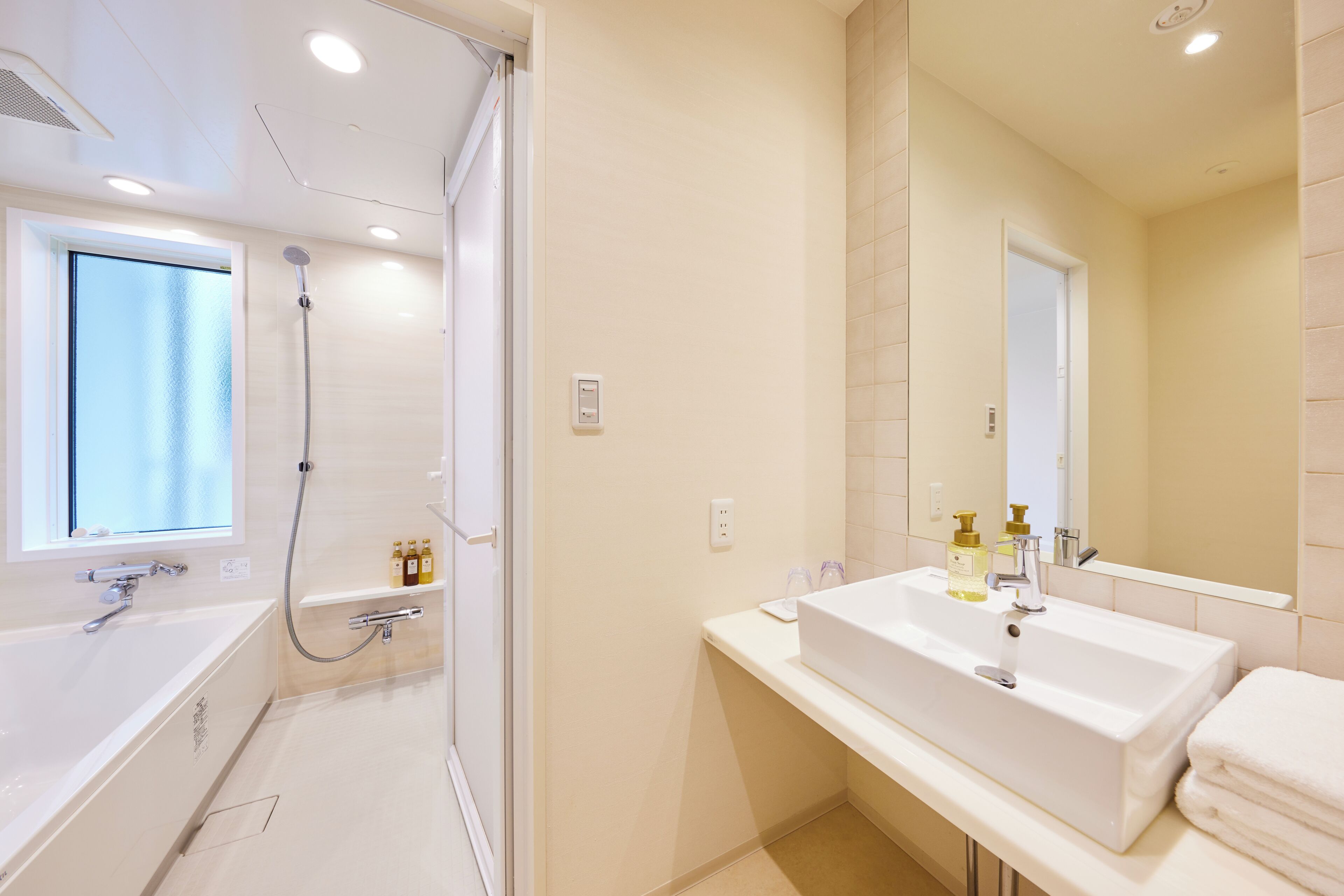 Une salle de bain moderne équipée d’une baignoire, d’une douche, d’un lavabo et d’un grand miroir.