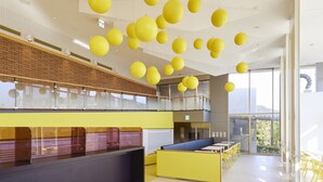 A spacious indoor area with a high ceiling, yellow hanging spherical decorations, and a seating area with tables and chairs. - Hotel Rotterdam Huis Ten Bosch (Sasebo)