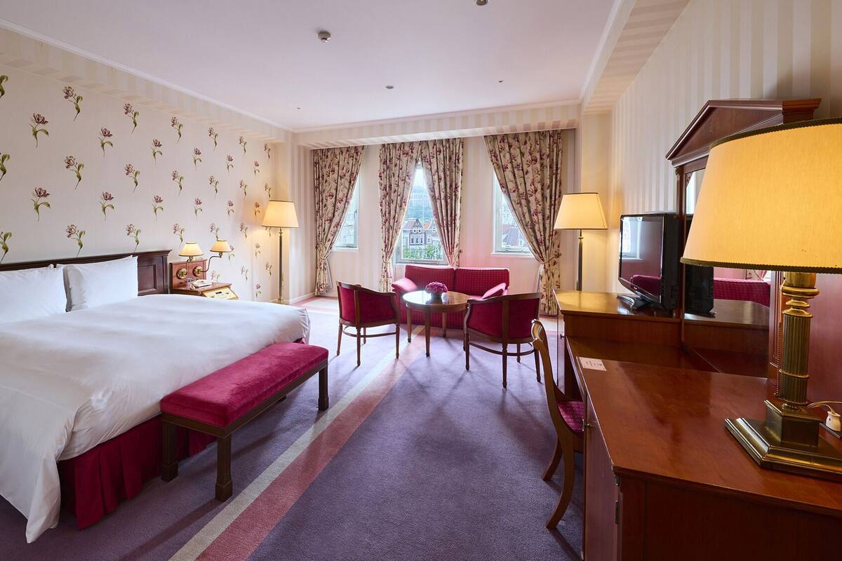Une chambre d’hôtel avec un grand lit, un bureau avec une lampe, une chaise, un canapé et un téléviseur.