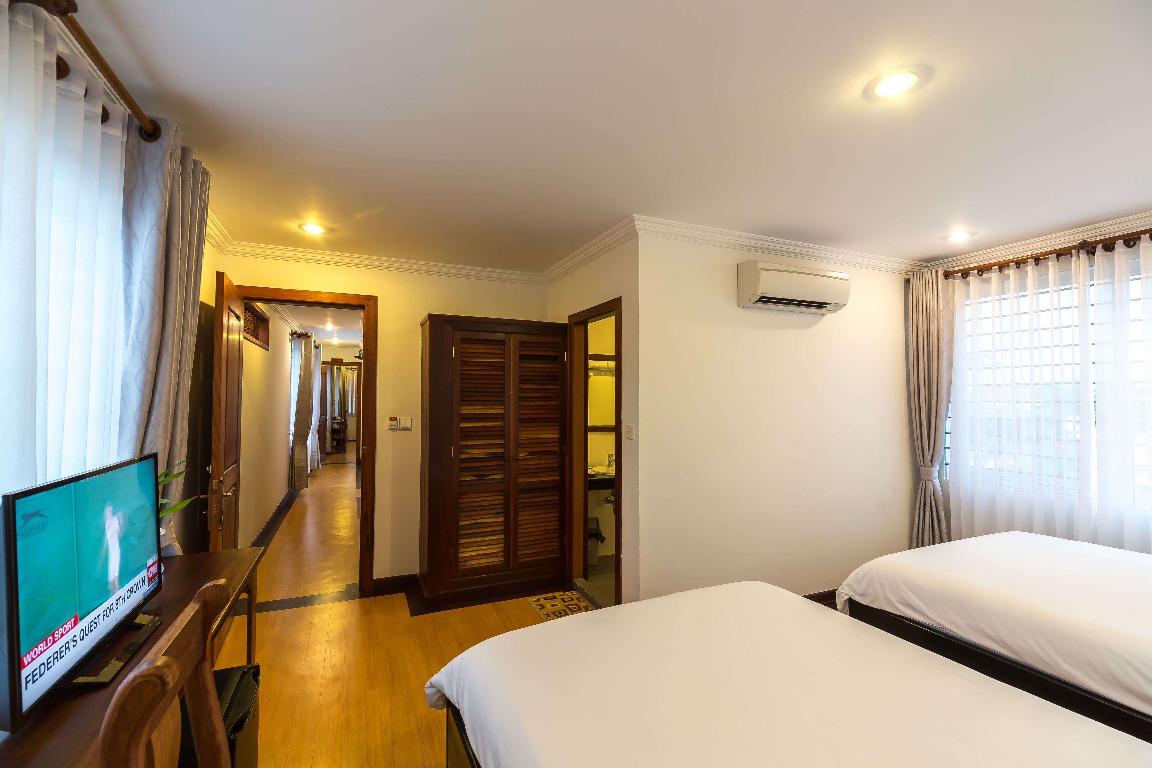 Una habitación de hotel con televisión, escritorio de madera, cama y armario.