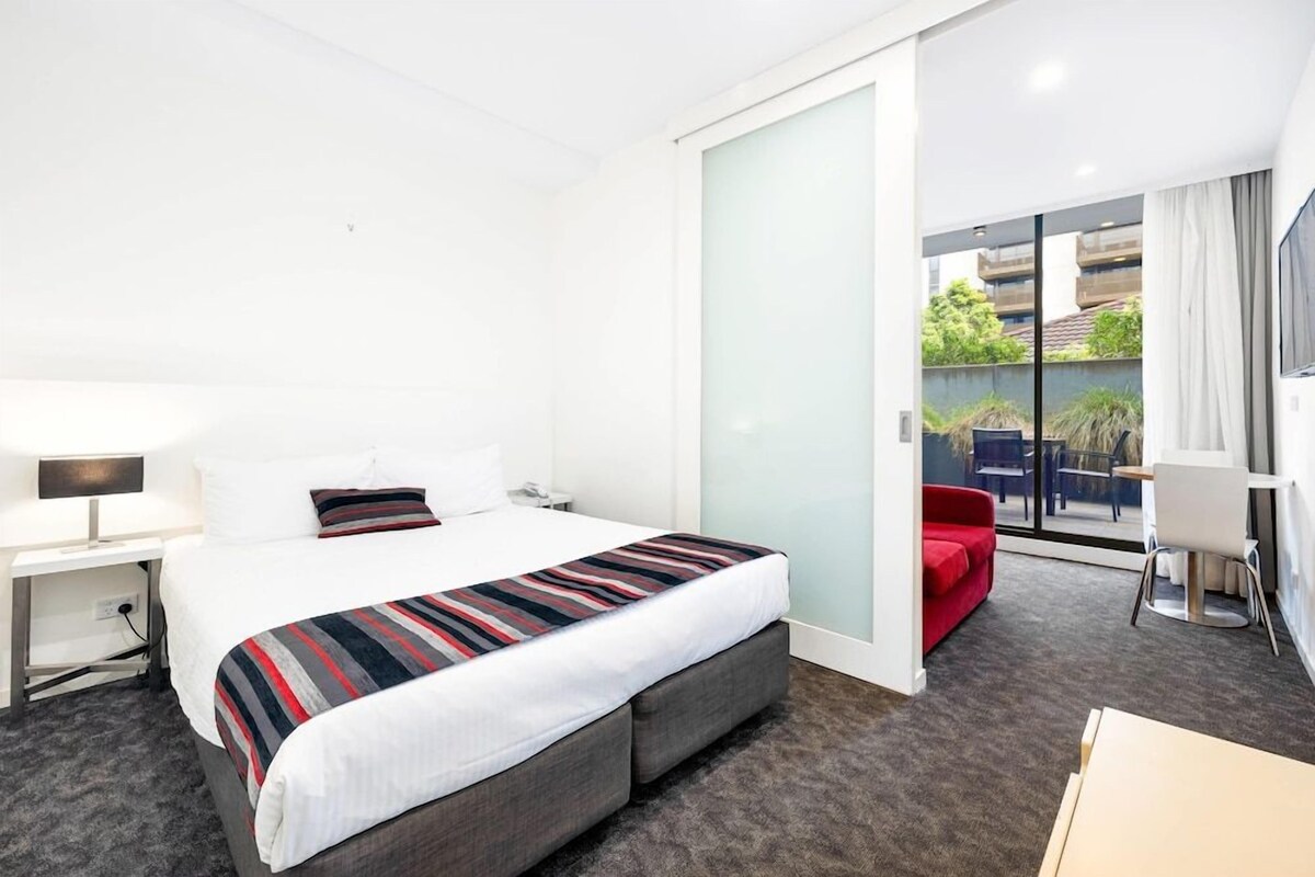 Un hotel moderno con una cama grande, un escritorio, una silla y vistas al exterior.