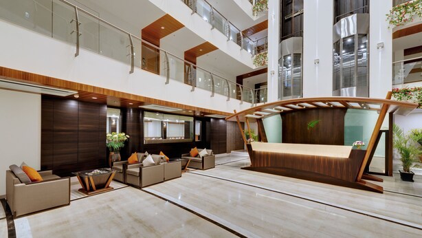 A spacious lobby with a modern sofa, seating area, and a unique curved bench. - The Fern Residency, MIDC - Pune (Pune)