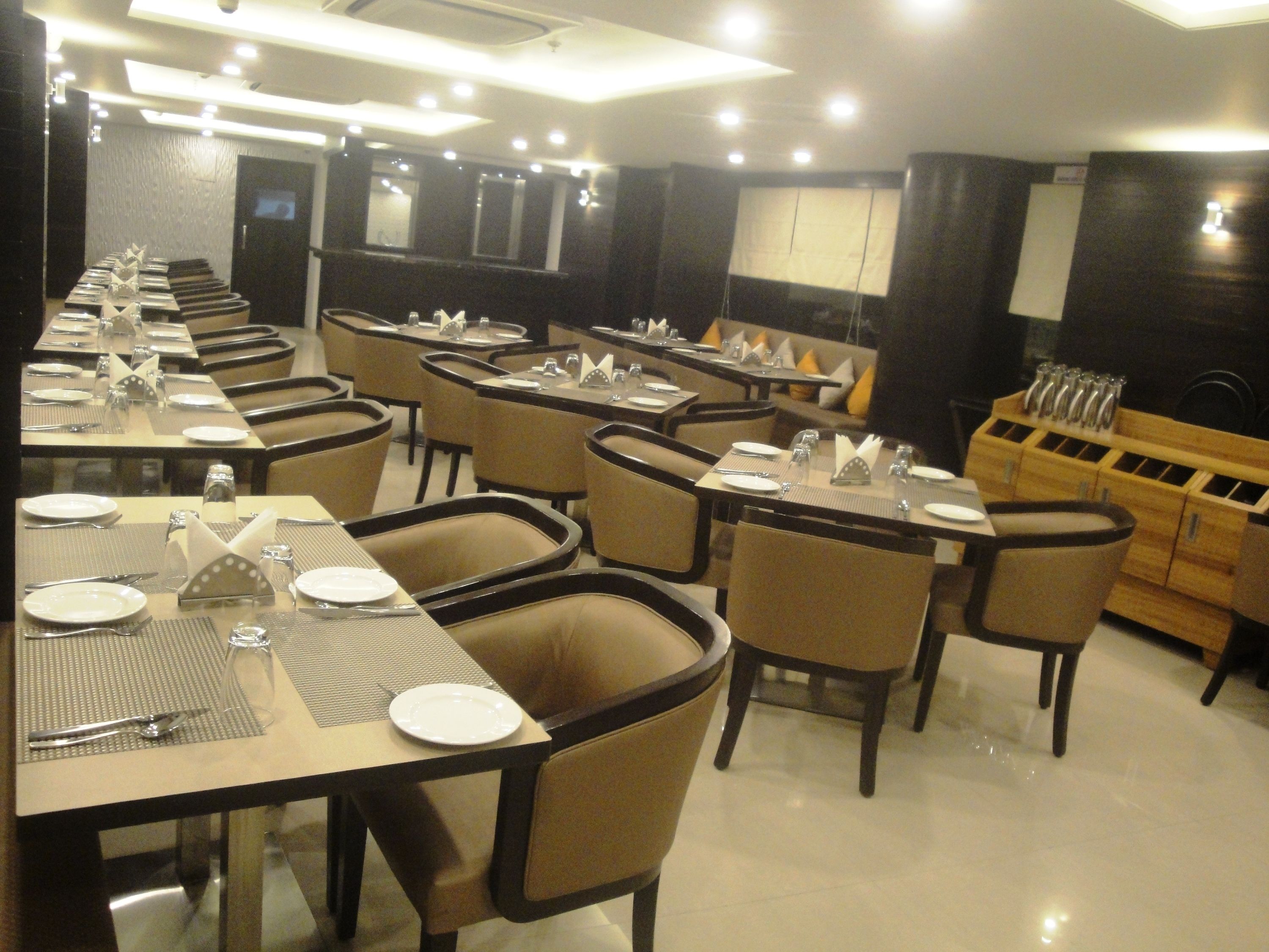 A restaurant with multiple dining tables set with plates, cutlery, and napkins.