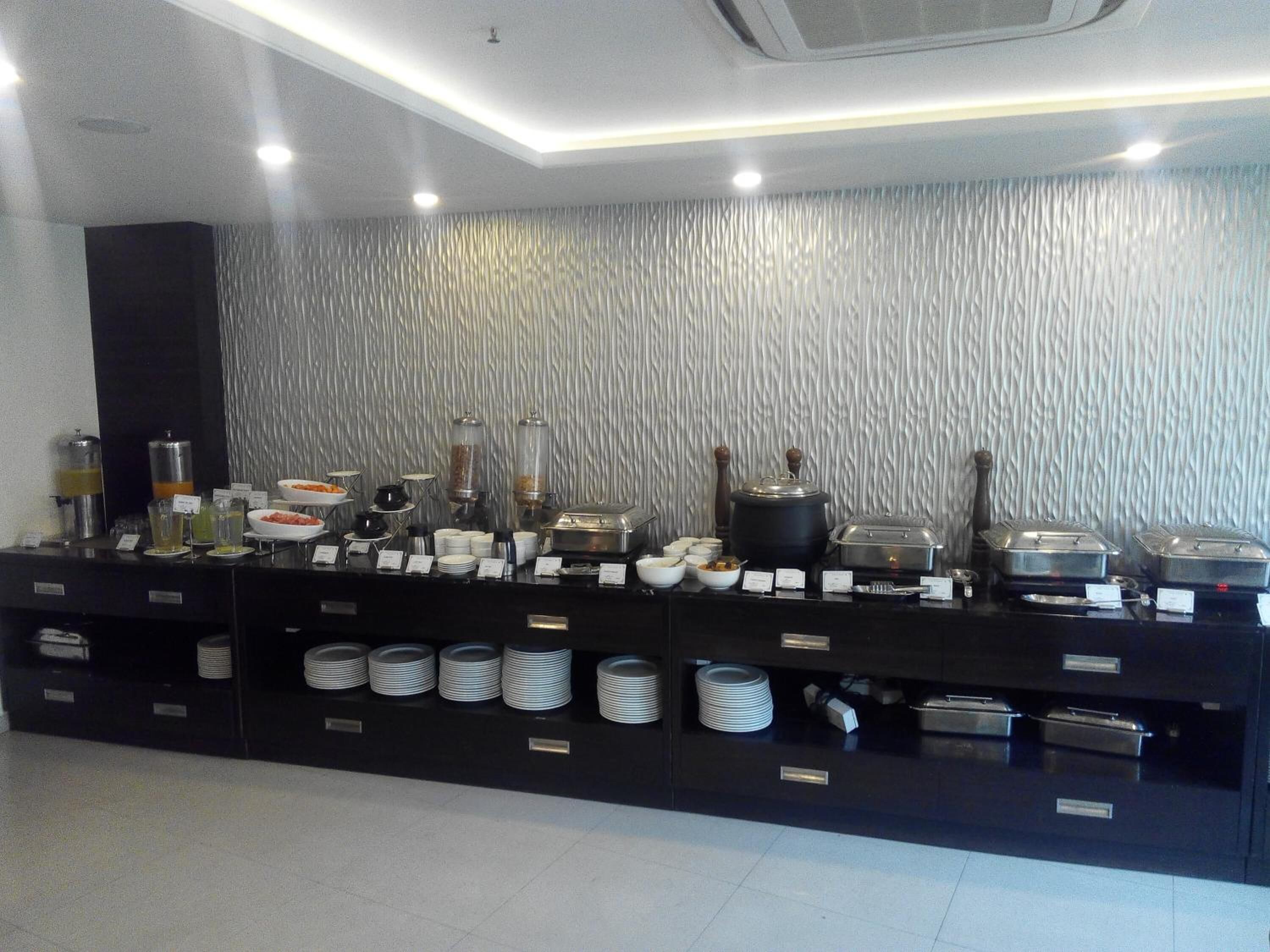 Un buffet proposant une variété de plats et d’accompagnements, disposés sur un comptoir noir avec un mur texturé en arrière-plan.