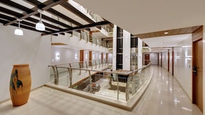 A modern hotel interior with a glass railing, a wooden sculpture, and a staircase leading to the upper floors. - The Fern Residency, MIDC - Pune (Pune)