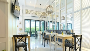 A modern dining area with multiple tables and chairs, large windows, and decorative lighting fixtures. - White Ivory Bed & Breakfast (Bangkok)