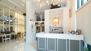 A modern interior with a reception desk, seating area, and a staircase leading to an upper level. - White Ivory Bed & Breakfast (Bangkok)