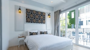 A modern bedroom with a large bed, bedside tables, a decorative wall panel, and a balcony with outdoor seating. - White Ivory Bed & Breakfast (Bangkok)