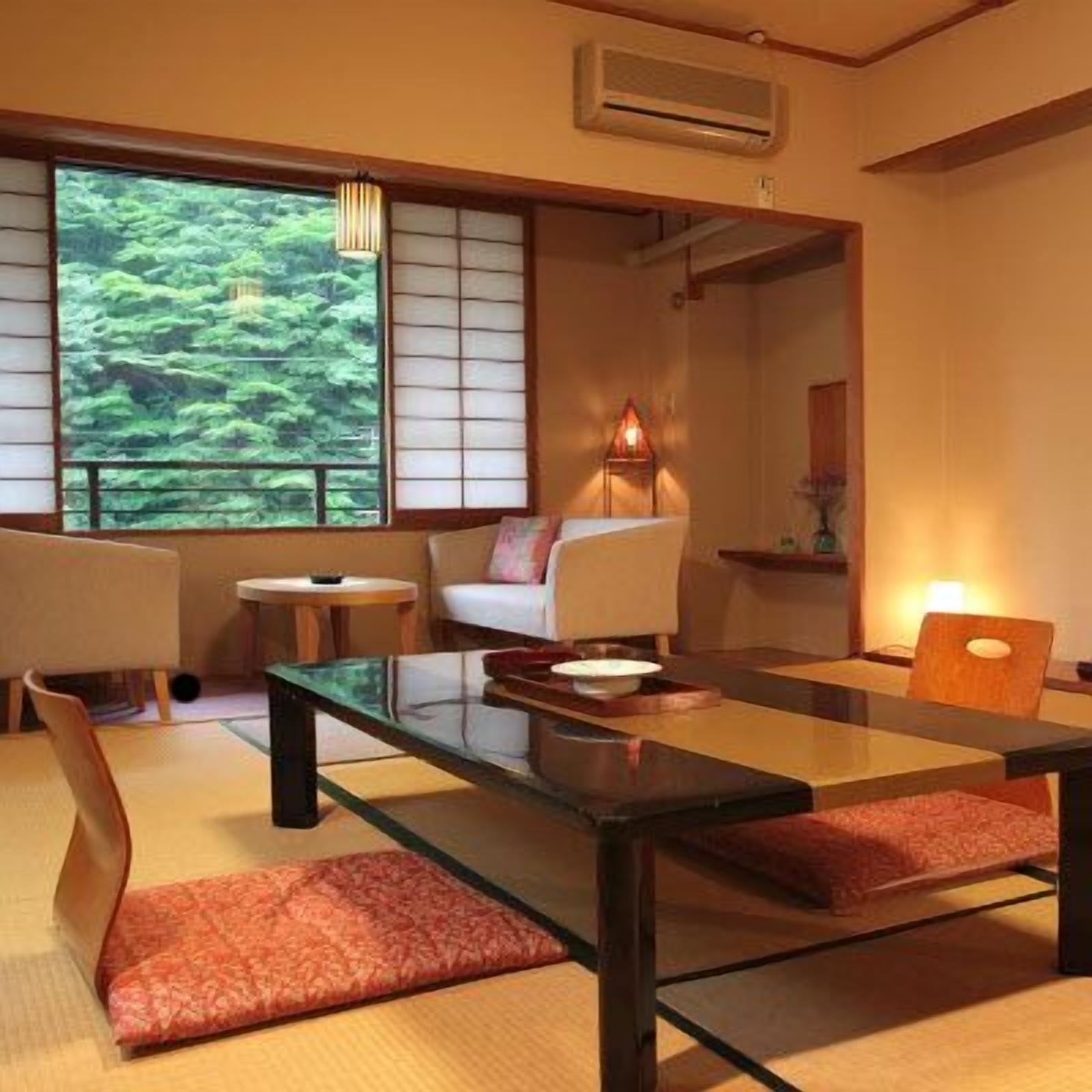 A traditional Japanese-style room with tatami flooring, a low table, a sofa, and a view of a forest through a shoji screen.