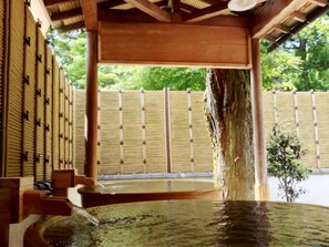 En traditionel japansk onsen med trækonstruktion, et træhegn og et lille haveområde.