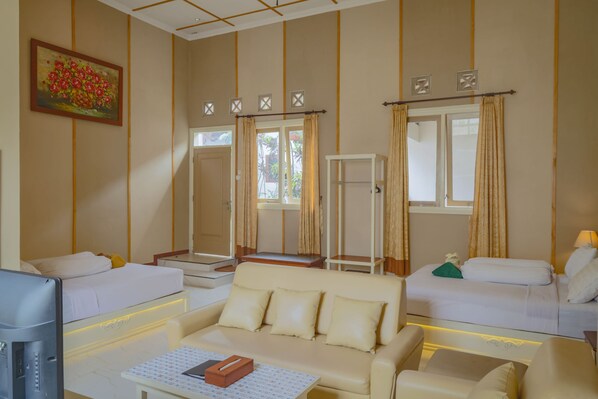 Habitación de hotel con dos camas, un sofá, un televisor y un cuadro en la pared.