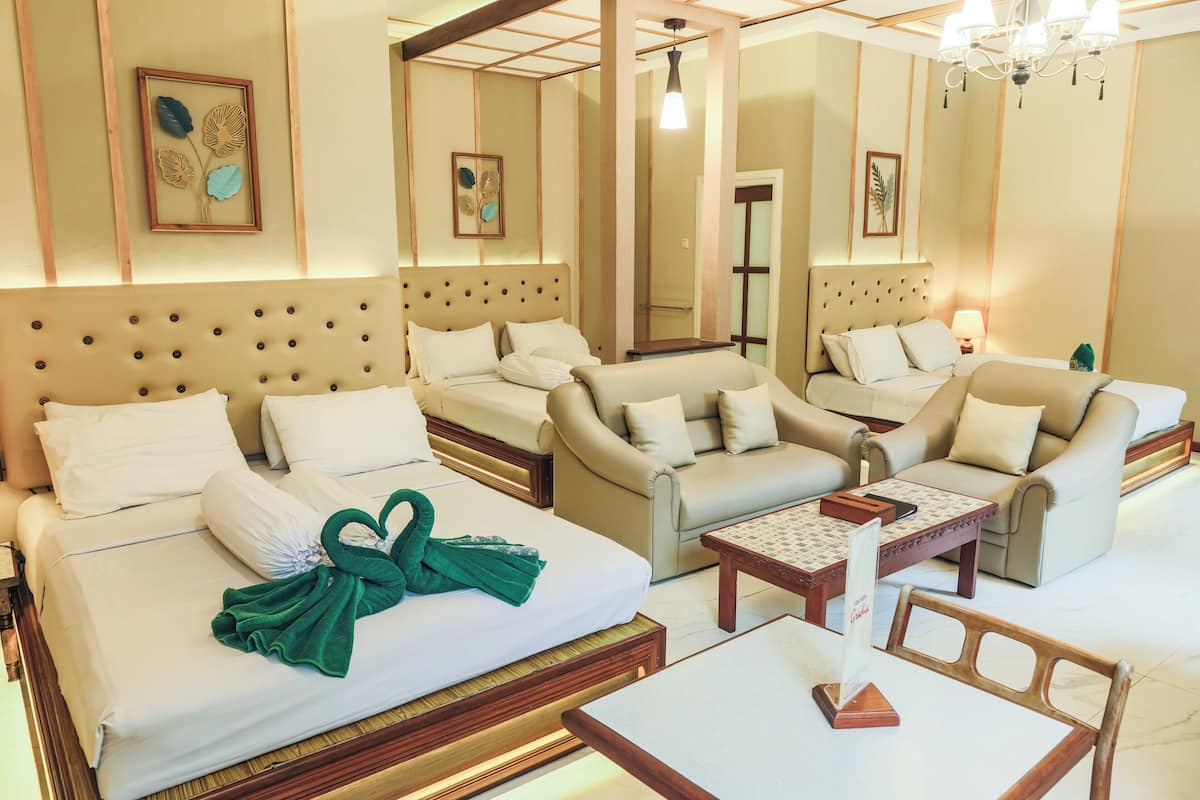 A hotel room with a large bed, two sofas, a small table, and a mirror.