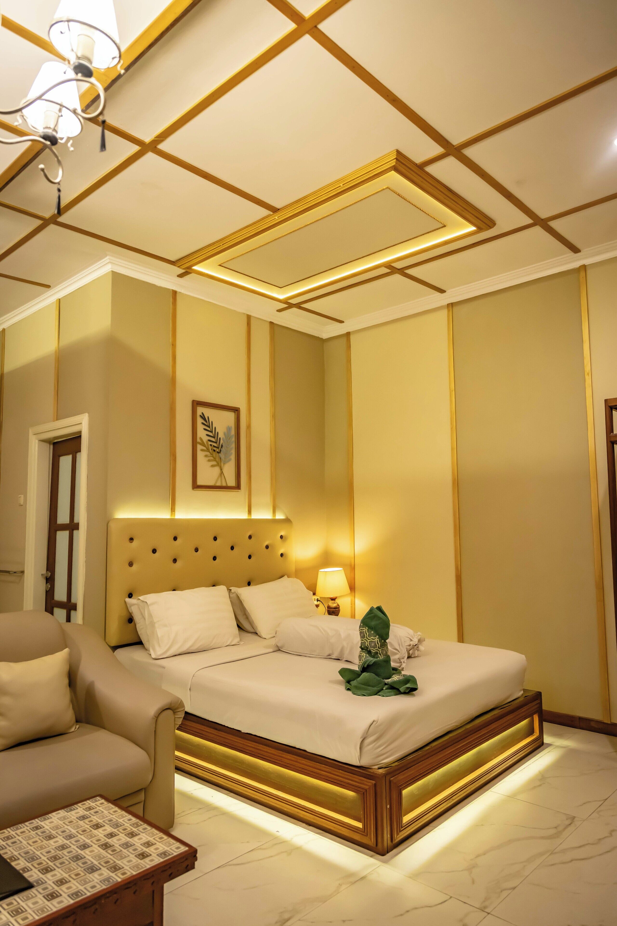 A hotel room with a large bed, a sofa, a small table, and a ceiling light fixture.