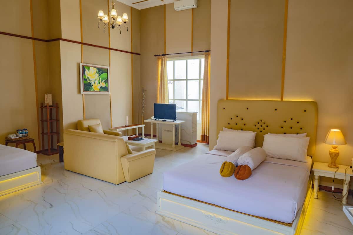 A hotel room with a bed, a desk, a chair, a sofa, and a painting on the wall.