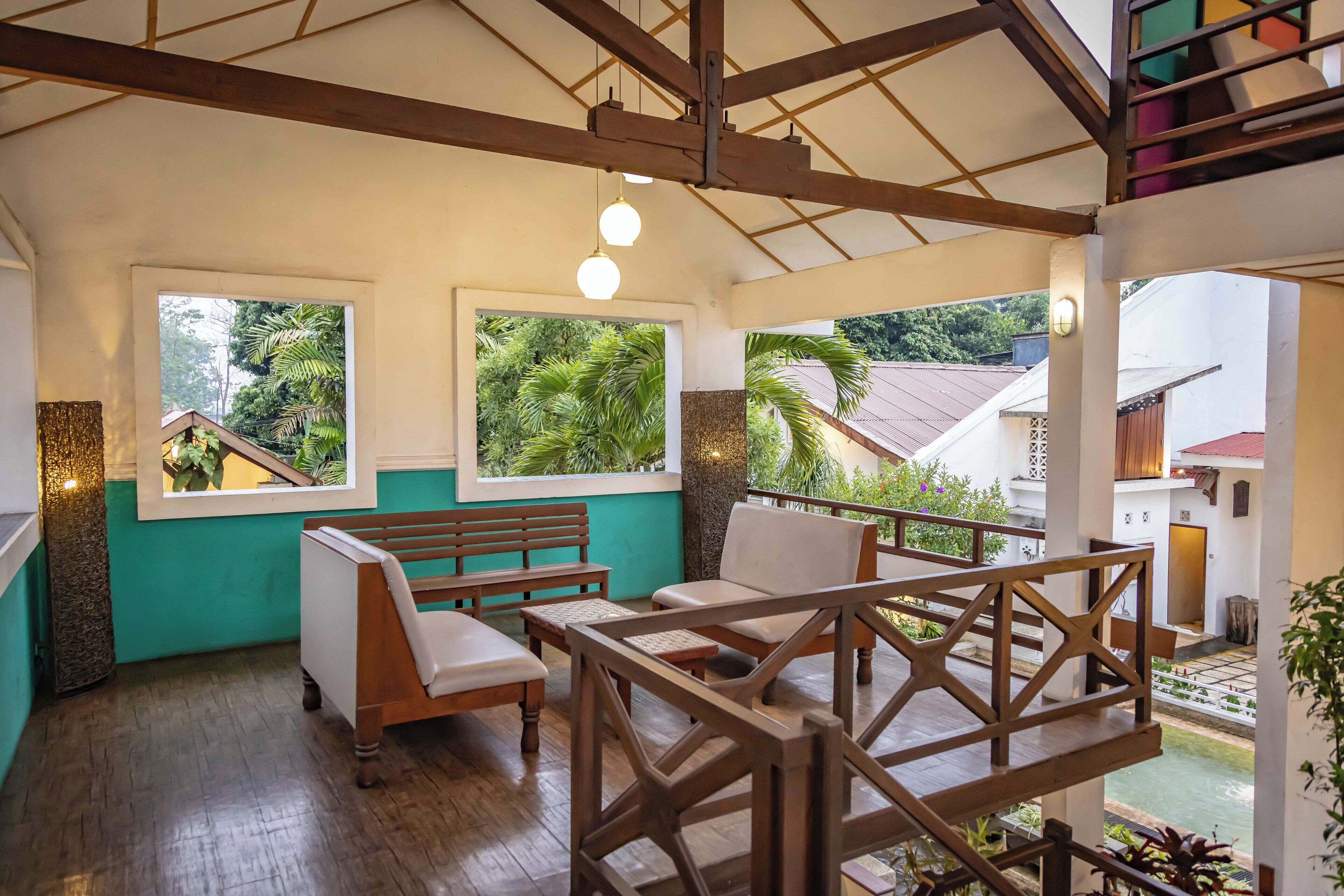 Una habitación amplia con muebles de madera, ventanas grandes y vistas al verde exterior.