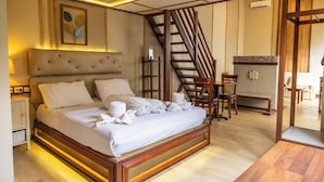 A neatly arranged bedroom with a large bed, wooden headboard, and a staircase leading to another room. - Hotel Gradia 2 (Batu)