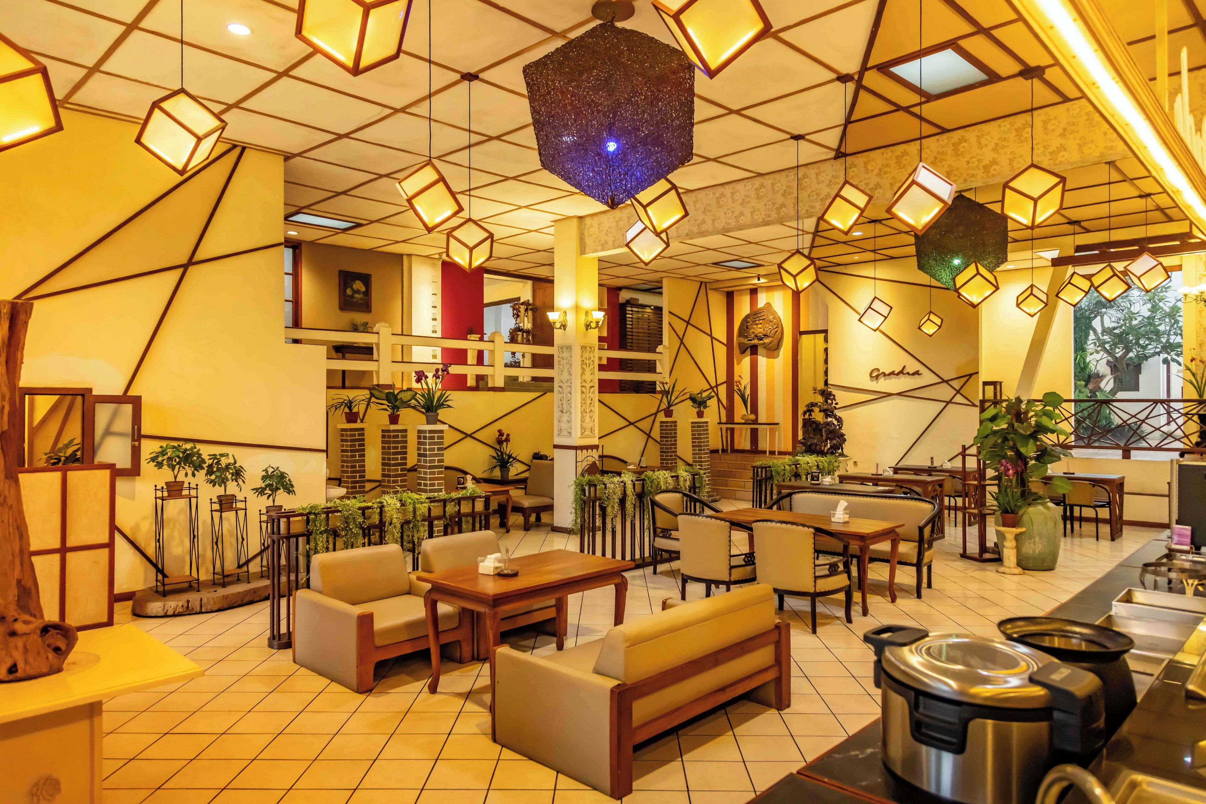 A spacious lobby with multiple seating areas, a reception desk, and a staircase leading to upper floors.