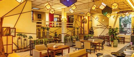 A spacious lobby with multiple seating areas, a reception desk, and a staircase leading to upper floors.