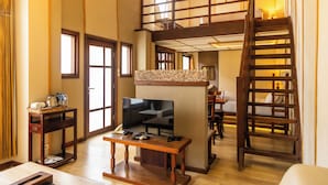 A spacious living area with a TV, wooden furniture, a balcony, and a staircase. - Hotel Gradia 2 (Batu)