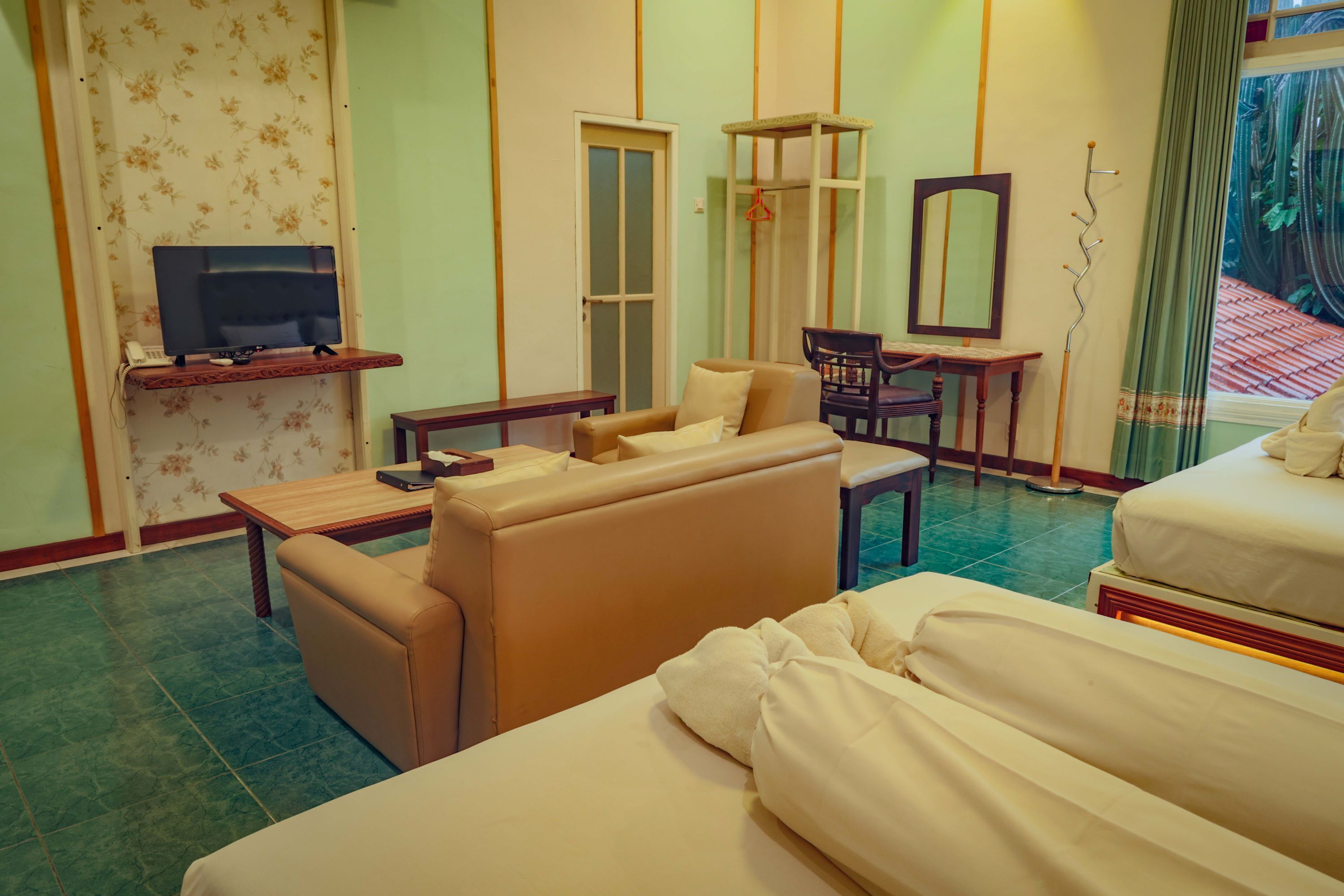 A hotel room with a sofa, a bed, a TV on a stand, a desk, and a chair.