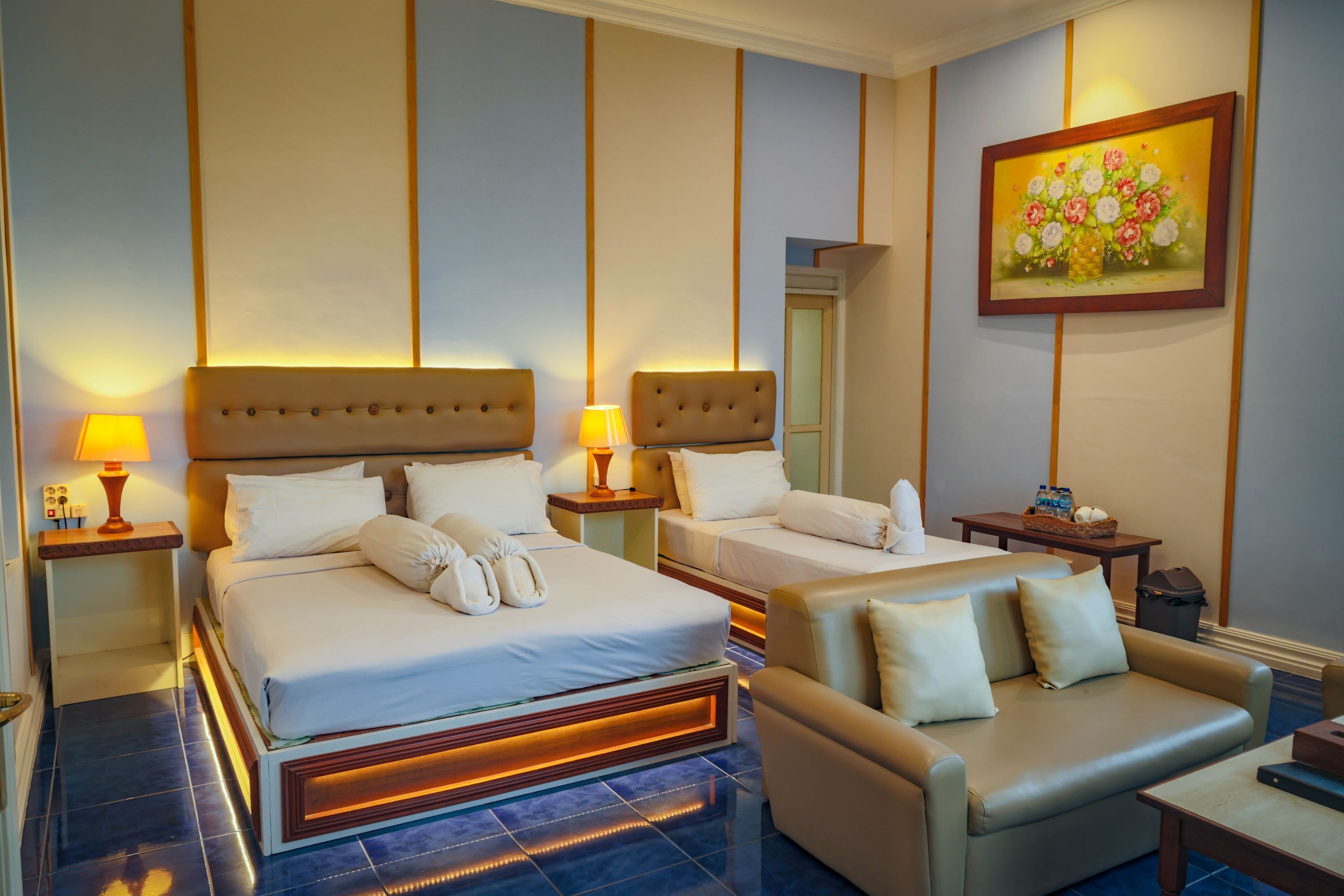 Une chambre d’hôtel avec deux lits, un canapé, une petite table et un tableau au mur.