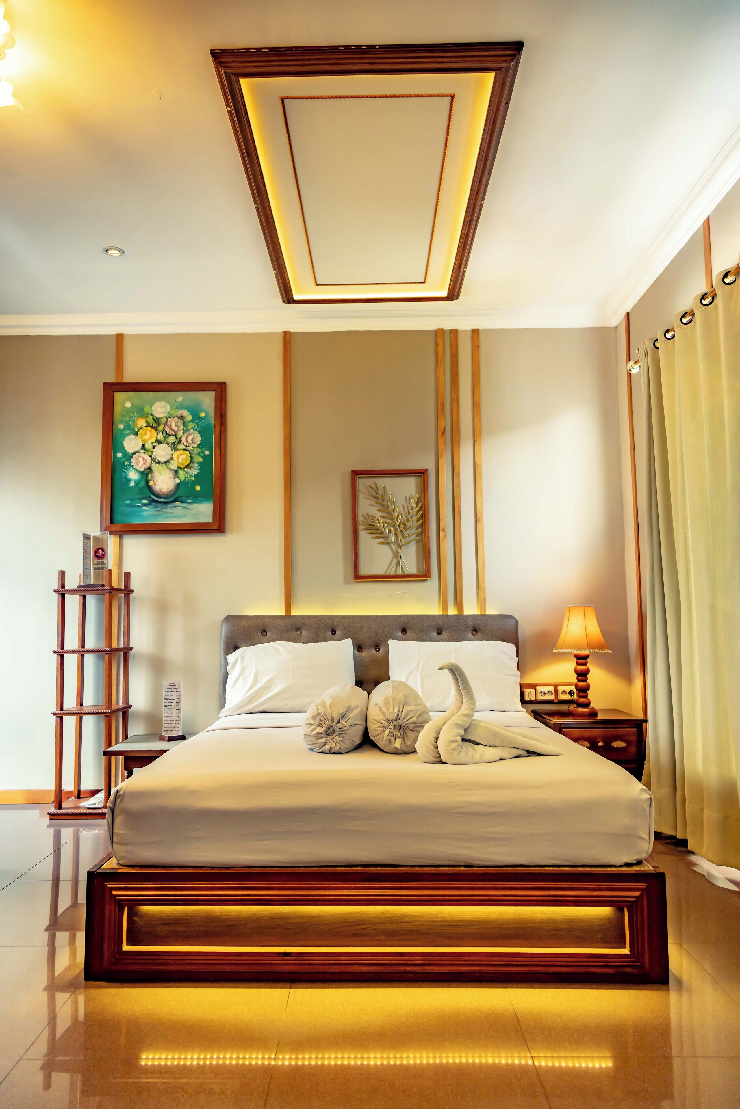 A neatly arranged hotel room with a large bed, a bedside table with a lamp, and a wall-mounted shelf.