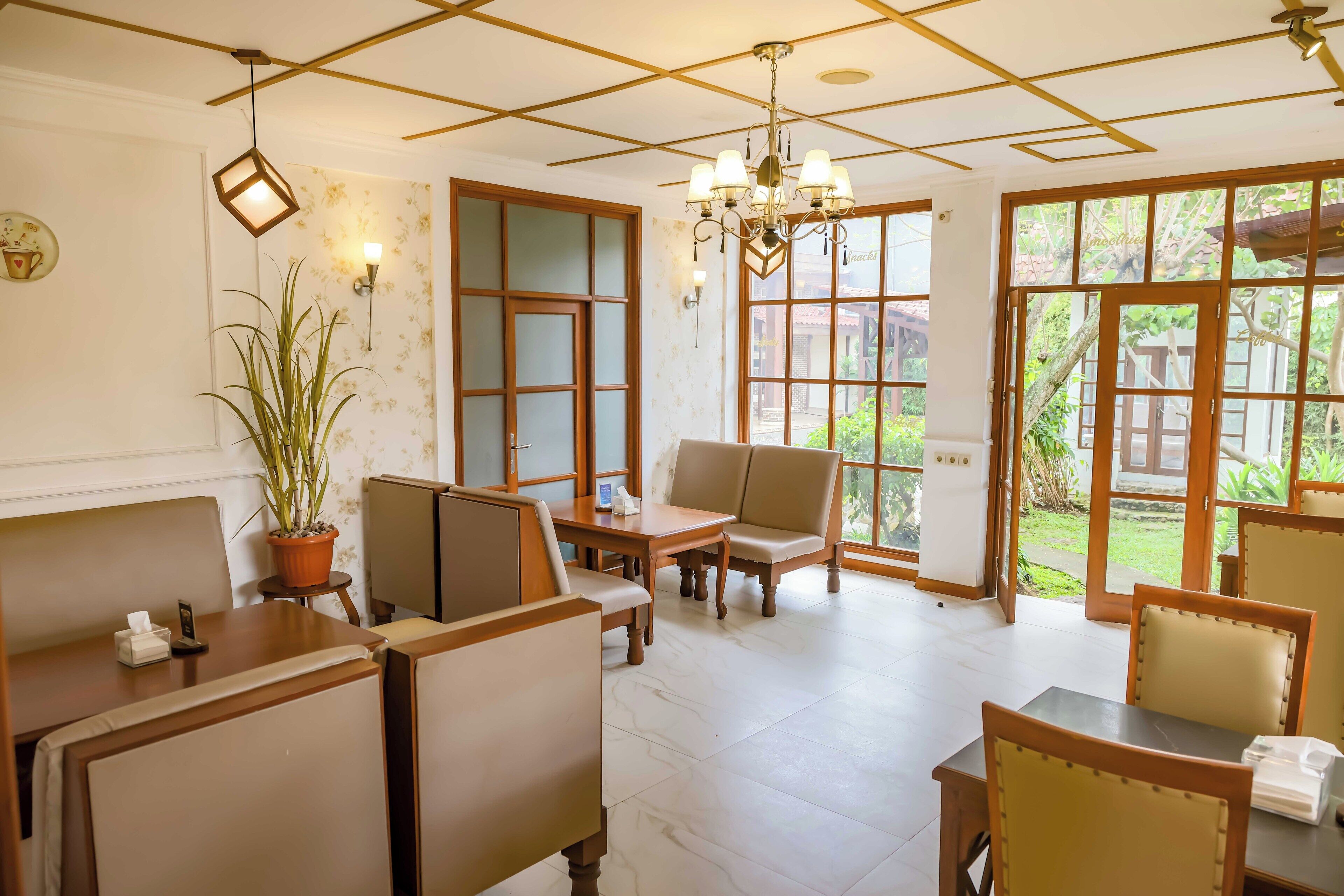 A cozy room with wooden furniture, a potted plant, and large windows offering a view of the outdoors.