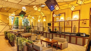 A cafe with a wooden bar, seating area, and decorative plants. - Hotel Gradia 2 (Batu)