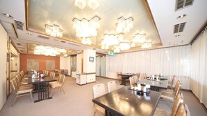 A hotel conference room with multiple tables and chairs, a reception desk, and a large chandelier. - Hotel Il Viale Hachinohe (Hachinohe)