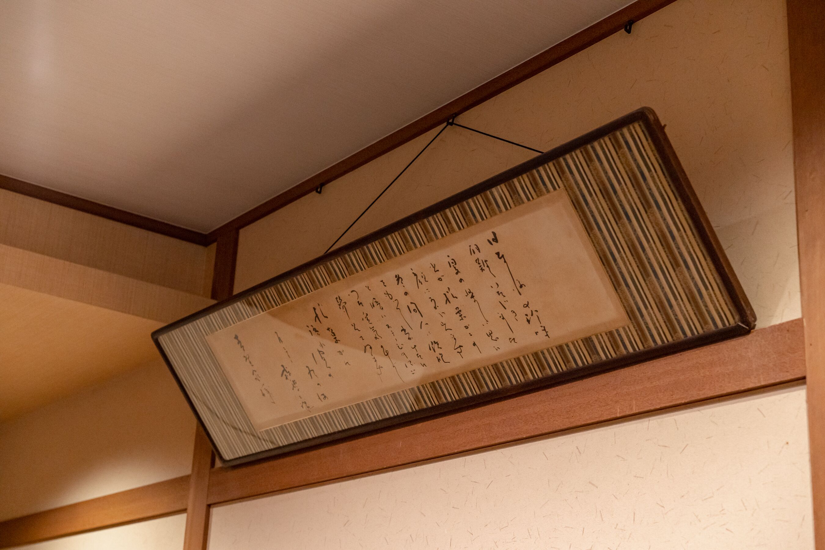 A traditional Japanese calligraphy hanging on a wall with wooden beams.
