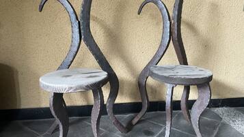 Dos sillas de metal con patas curvas frente a una pared con textura.