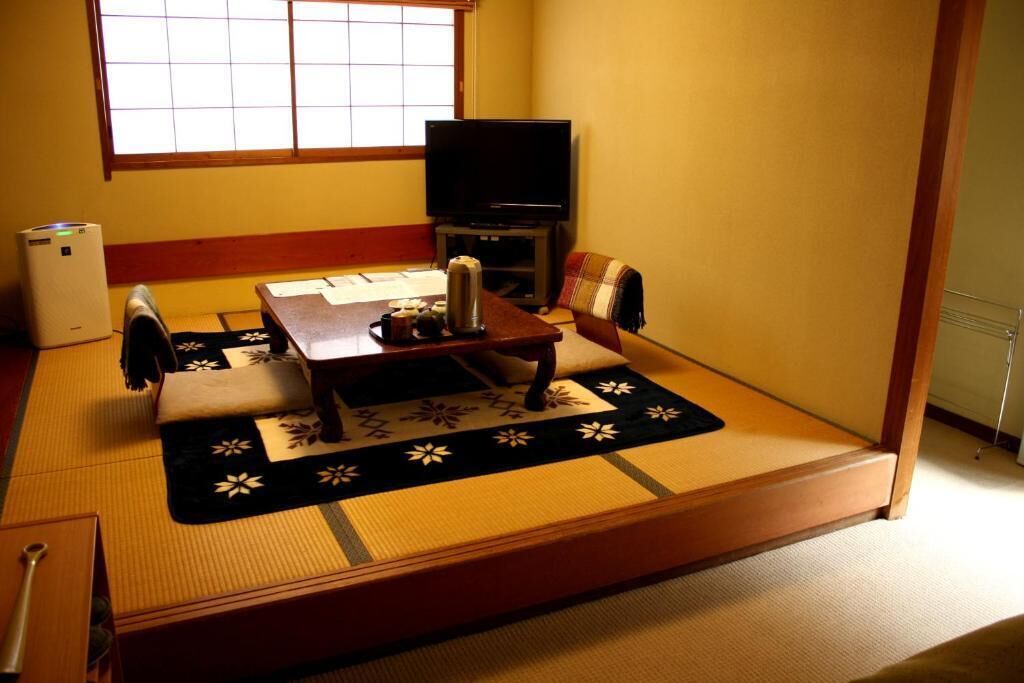 A tatami mat room with a low table, a television, and a heater.