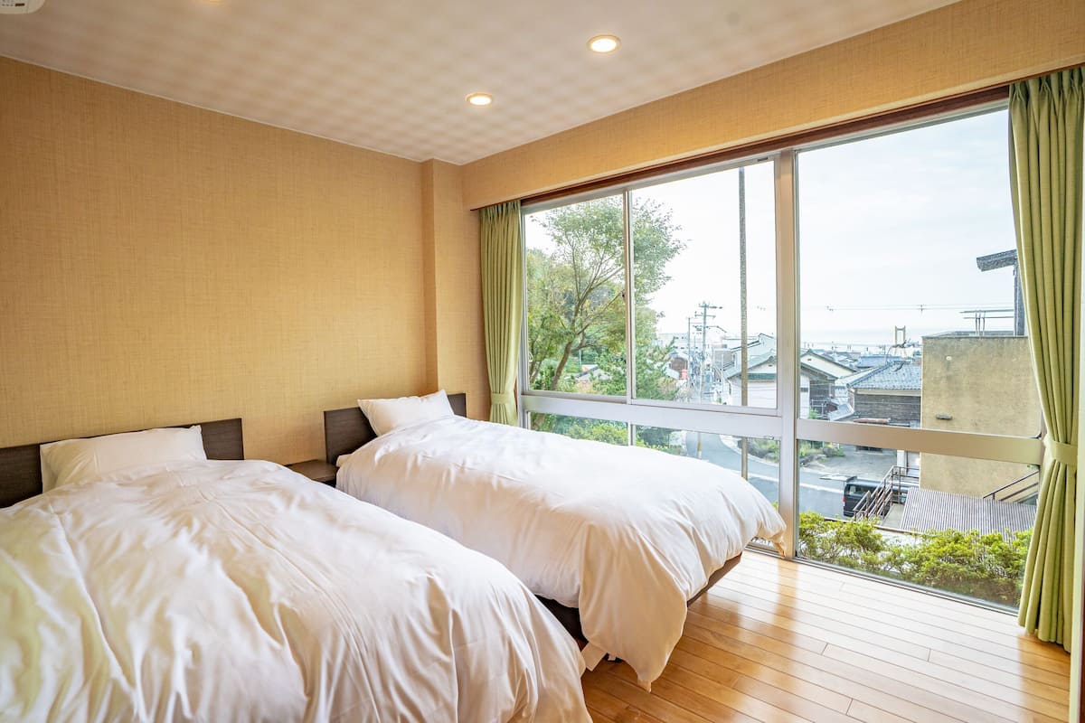 Een hotelkamer met twee bedden, een groot raam met uitzicht op de stad en een houten vloer.