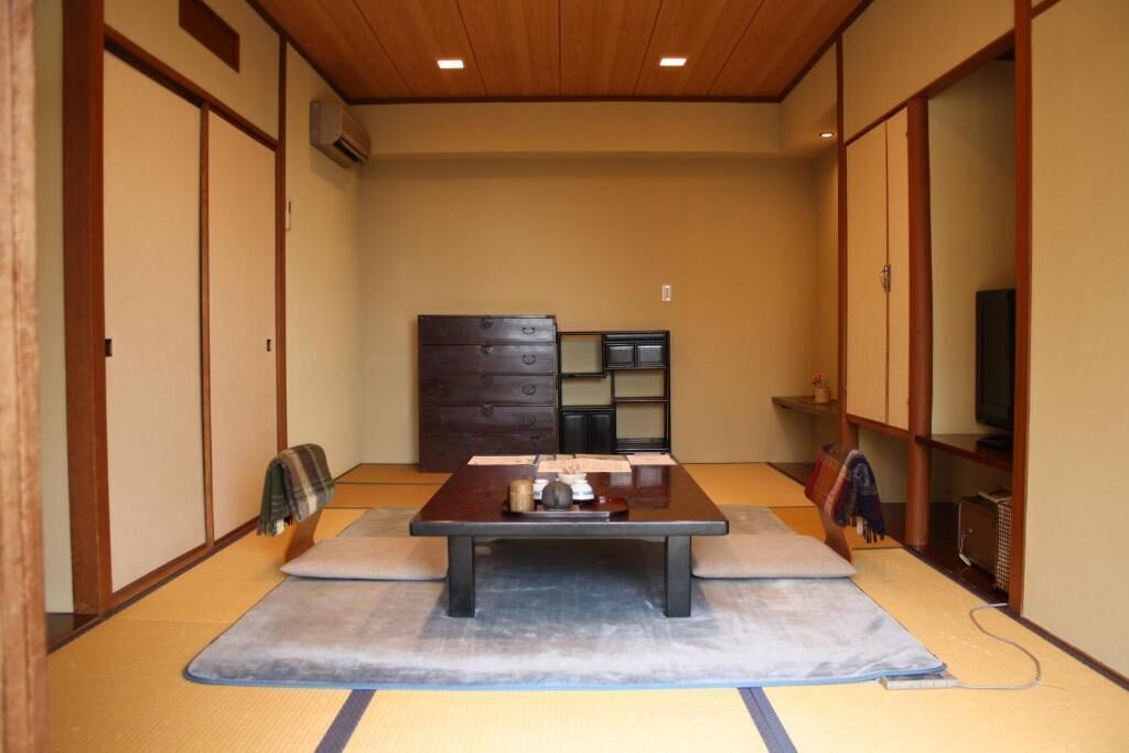 Una habitación japonesa tradicional con suelo de tatami, una mesa de madera baja y puertas correderas.