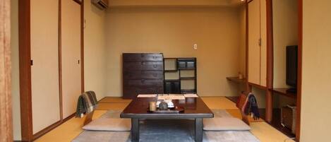 Una habitación japonesa tradicional con suelo de tatami, una mesa de madera baja y puertas correderas.