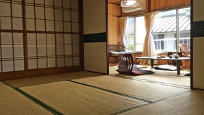 A tatami mat room with a sliding door leading to a balcony with a table and chairs. - Fukushimakan (Hakone)