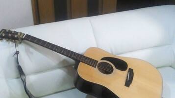 Una guitarra sobre un sofá blanco con un adaptador de corriente enchufado.