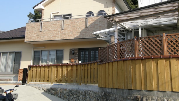 Une maison à deux étages avec un balcon, un mur en pierre et une clôture en bois.
