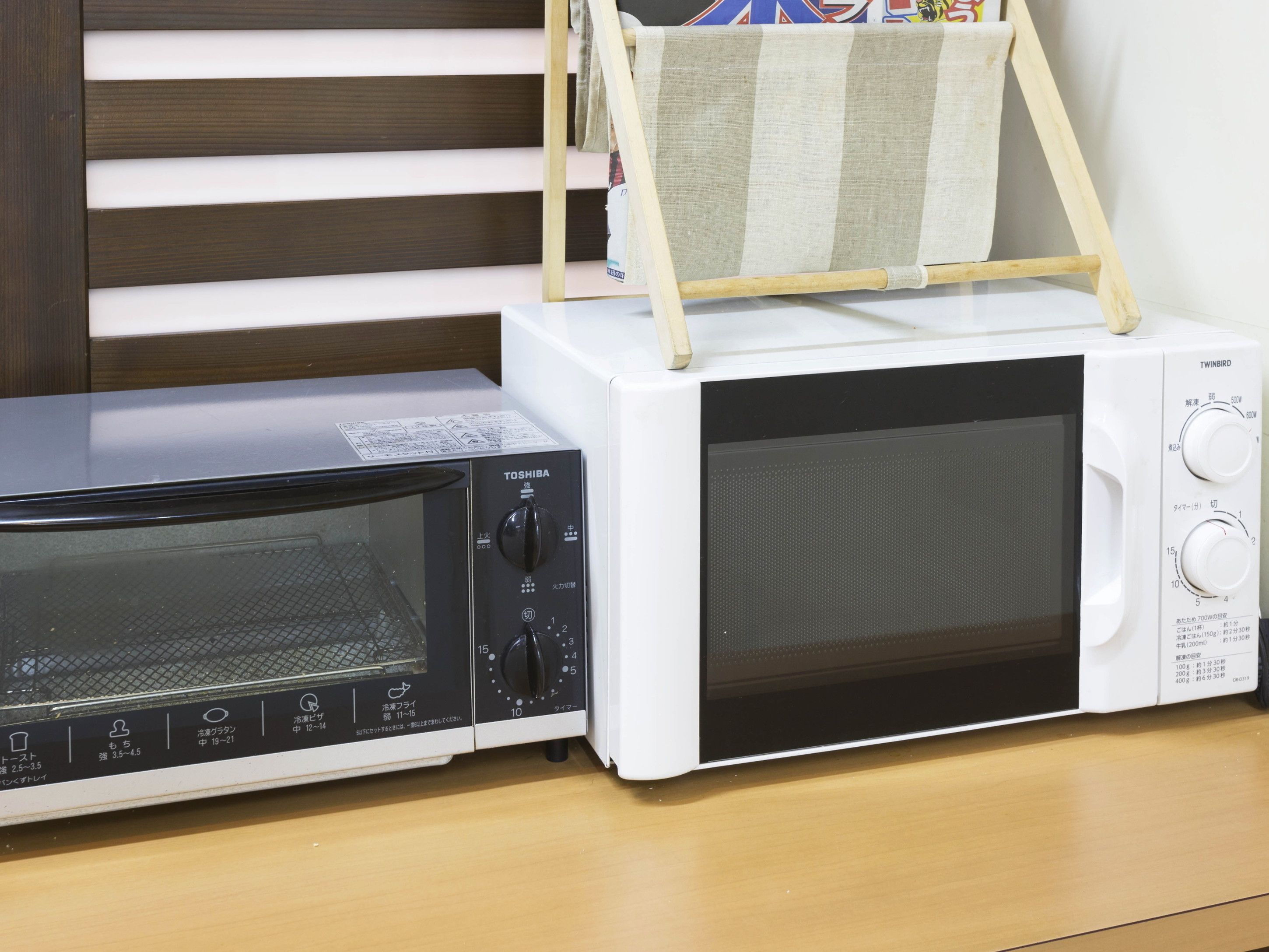 A white microwave oven with a black control panel and a wooden shelf on top.