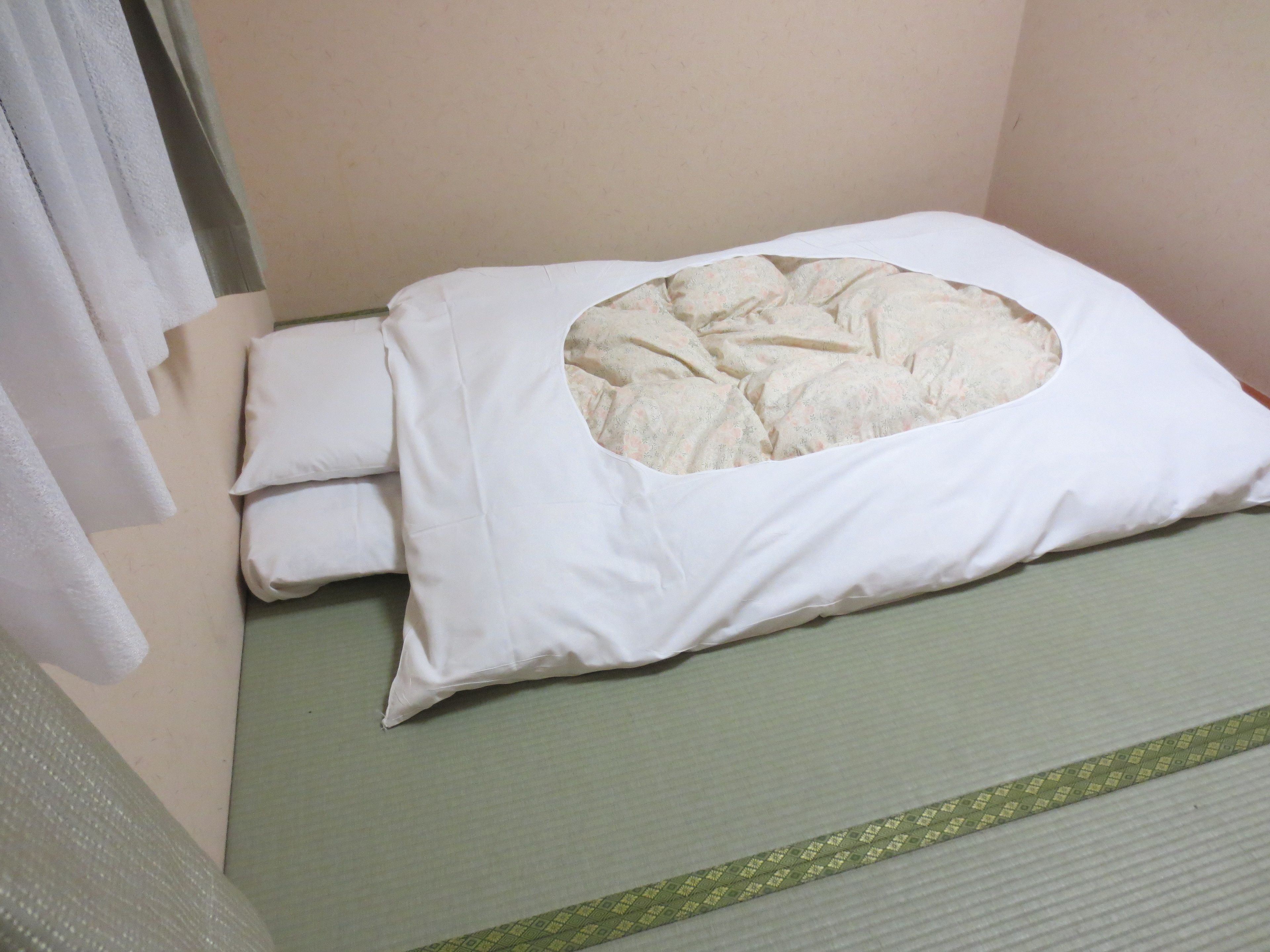 Un letto con un materasso verde e un cuscino bianco con un'apertura circolare.