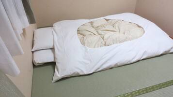 Un letto con un materasso verde e un cuscino bianco con un'apertura circolare.